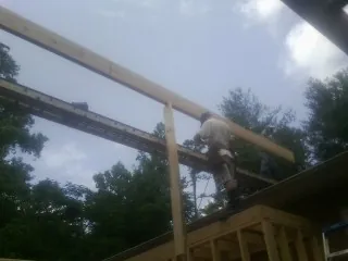 Carpenter setting a ridge beam over a new addition frame — Ice Dam Removal by Roofing Brothers in Weldon