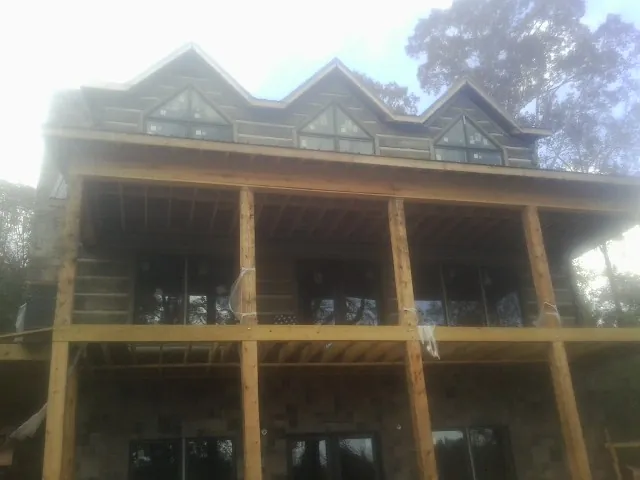 Dormers and porch framing on a large log home under construction — Roof Coating work by our crew in Weldon