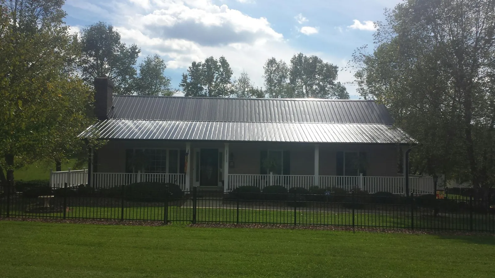 Gray metal roof on a brick ranch with a full width front porch — Gutter Guard Installation work by our crew in Weldon